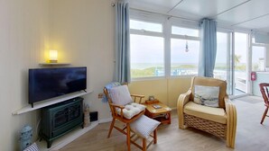 En stue med fjernsyn, to stole, et lille bord og en sofa.