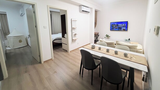 Ein modernes Hotelzimmer mit Essbereich, einem Bett, einem Fernseher und einem kleinen Balkon.
