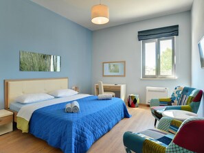 Un dormitorio con cama, escritorio, silla y ventana con cortinas.