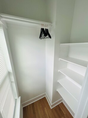 Ein Schrank mit weißen Regalen und einer Kleiderstange.