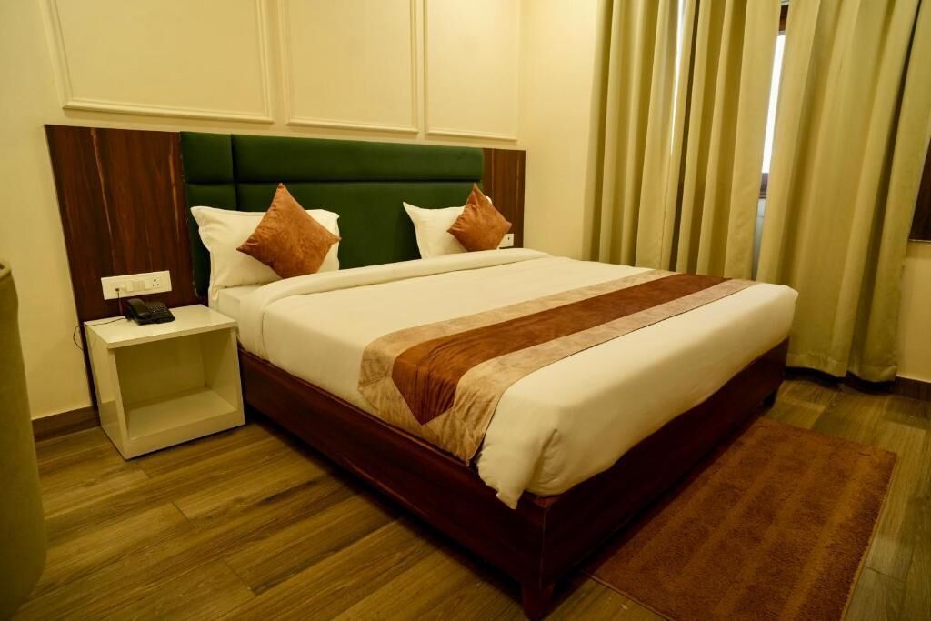 Une chambre d’hôtel avec un lit, une table de chevet, un plancher en bois et une fenêtre avec des rideaux.