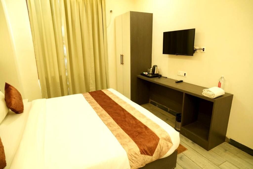 A hotel room with a bed, a desk, a television, and a wardrobe.