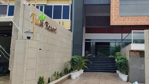 Entrada de hotel con un cartel que dice 'Hilton Resort', un conjunto de escalones que llevan a la entrada y plantas en macetas a lo largo del camino.