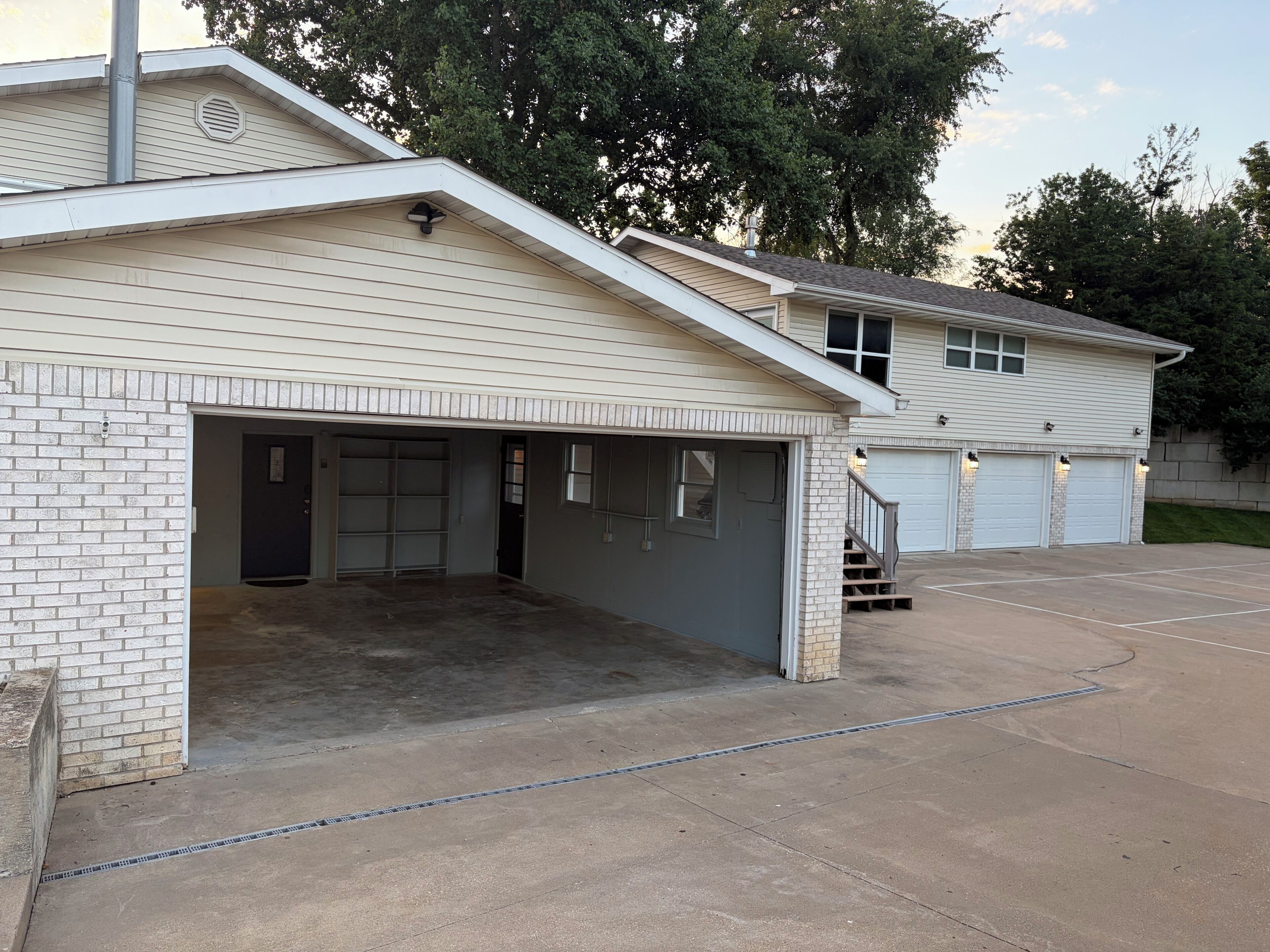 A two-story building with a garage, a covered driveway, and a brick wall.
