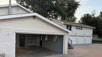 A two-story building with a garage, a covered driveway, and a brick wall.