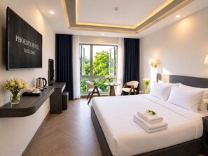 Une chambre d’hôtel avec un lit, un bureau, une télévision et une vue sur la verdure environnante.
