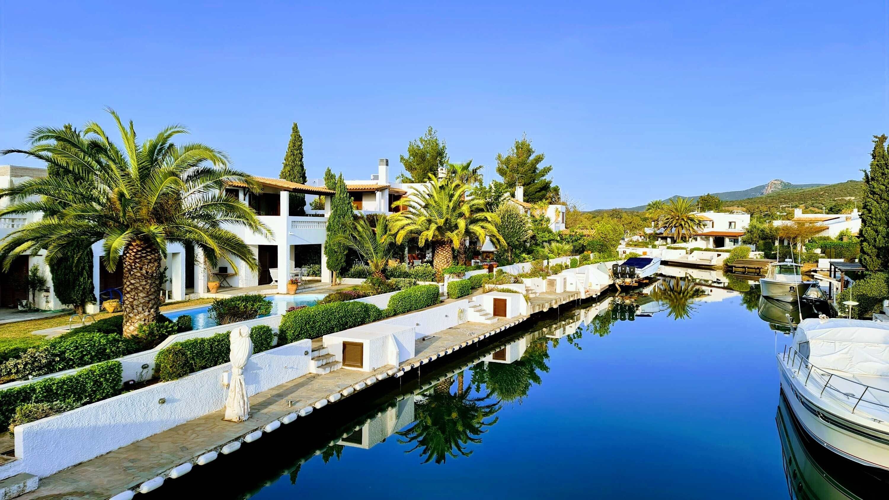Un puerto deportivo con barcos, una piscina y edificios blancos con balcones.