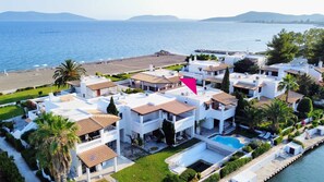Un hotel a la costa amb diversos edificis blancs, una piscina i vistes a la platja.