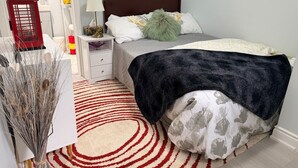 Une chambre à coucher avec un lit, une table de chevet, une lampe et un téléphone public rouge.