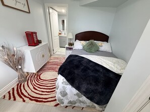 Un dormitorio con cama, mesita de noche, lámpara y un teléfono rojo.