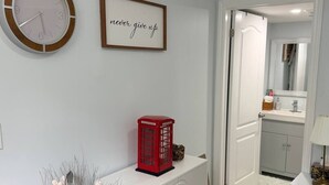 Une pièce avec une console blanche, un téléphone public rouge, une citation inspirante encadrée et un miroir en arrière-plan.