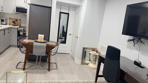 Une cuisine moderne avec une table à manger, des chaises, un téléviseur et une petite table d’appoint.