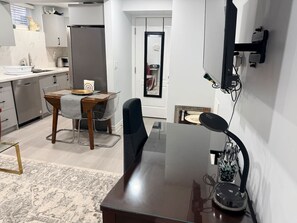 Una cocina moderna con comedor, un televisor de pantalla plana montado en la pared y una pequeña mesa con sillas.