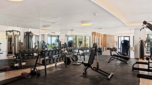 Ett gym med olika typer av träningsutrustning, inklusive hantlar, kettlebells och styrketräningsmaskiner.