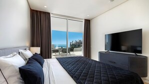 Ett hotellrum med en säng, en TV, ett skrivbord och utsikt över staden.
