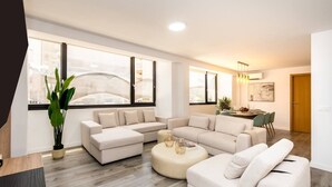 Una sala de estar moderna con un sofá modular, una mesa de centro redonda y un comedor con sillas.