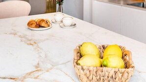 Una cocina moderna con encimera de mármol, frutero y cafetera.
