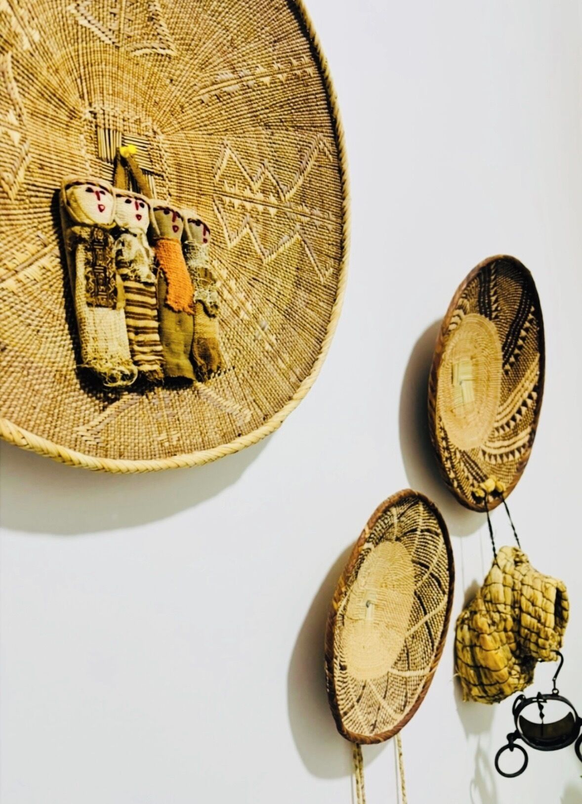 Un panier tressé orné d’un motif géométrique, un petit objet tressé doté d’une anse, et un objet tressé destiné à être suspendu.