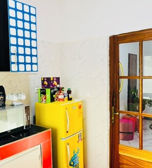 A kitchen with a microwave, a yellow refrigerator, and a blue wall decoration. - 2-bedroom apartment in charming Dakar with AC and comfort (Dakar)