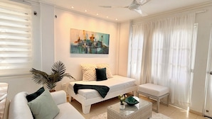 A modern living room with a white sofa, a coffee table, a ceiling fan, and a painting on the wall. - Casa Dimares | Private villa for 23 guests with a pool, 1 minute from the beach (La Boquilla)