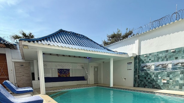 A swimming pool with lounge chairs, a covered seating area, and a tiled wall with a dolphin mural. - Casa Dimares | Private villa for 23 guests with a pool, 1 minute from the beach (La Boquilla)