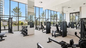 Un gimnasio moderno con equipos de ejercicio variados, ventanas amplias y vistas a la ciudad.