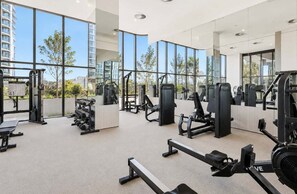 Ein modernes Fitnessstudio mit verschiedenen Trainingsgeräten, großen Fenstern und Blick auf die Stadt.