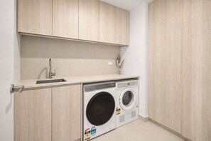Ein Waschraum mit Waschmaschine, Spüle und Holzausbau.