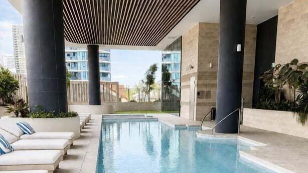 Una piscina con sillas de descanso, rodeada de arquitectura moderna y plantas.