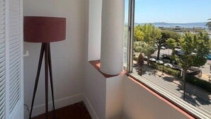 Ein Eckzimmer mit großem Fenster, einer Stehlampe und einem gewebten Korb.