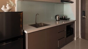 Een moderne keuken met een roestvrijstalen koelkast, een spoelbak, een waterkoker en een magnetron.