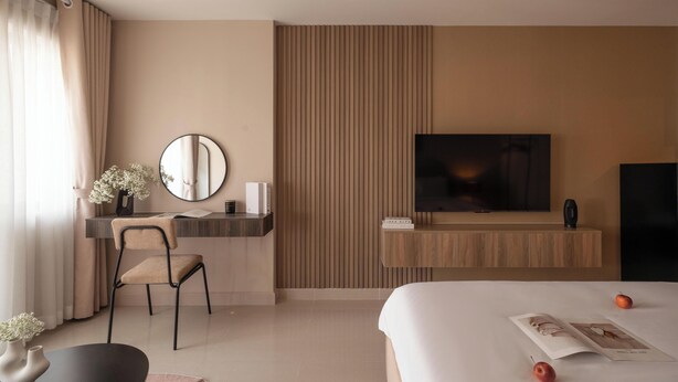 Een hotelkamer met een bed, een bureau met een stoel, een televisie en een spiegel.
