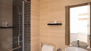 Een moderne badkamer met een glazen douchecabine, toilet, wastafel met een groot wasbakgedeelte en een spiegel.