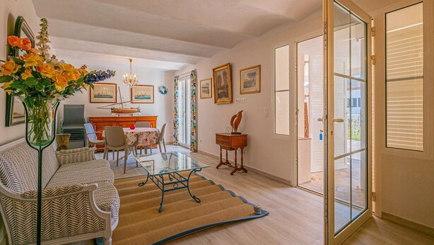 Uma sala de estar ampla com uma mesa de jantar, cadeiras, um sofá, uma mesa de centro e uma janela grande.