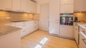 Uma cozinha moderna com armários brancos, forno embutido e bancada.