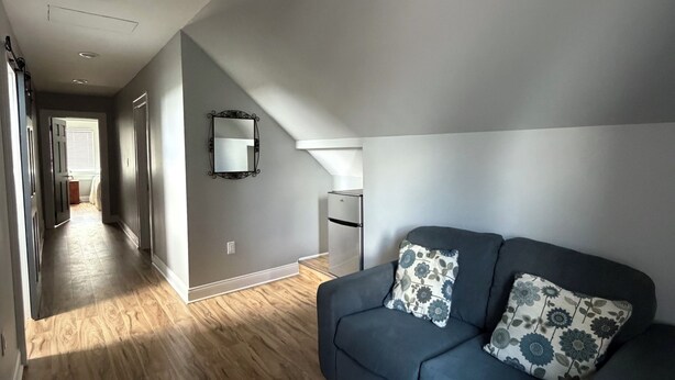 Una sala de estar moderna con un sofá azul, piso de madera y un pasillo que conduce a una cocina.