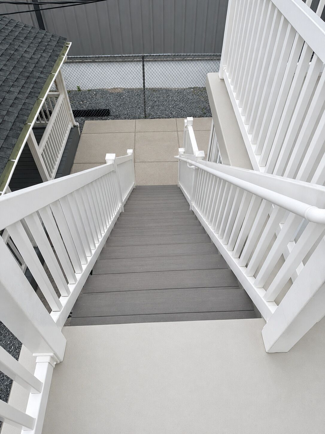 A staircase with white railings leading to a covered area with a grey roof.