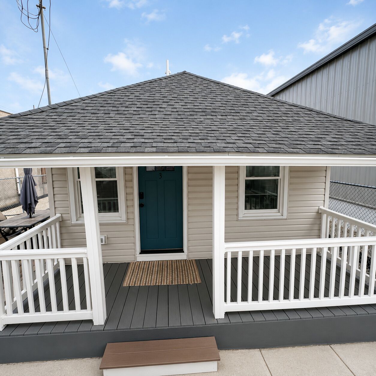 A small house with a dark blue door, white railings, and a grey roof.