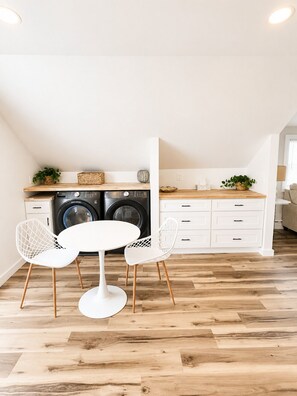 A compact kitchen with a washing machine, a dining table with chairs, and a white cabinet. - Spacious 3 Unit 7-bedroom house in Wildwood with Central AC (Wildwood)