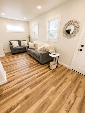 A living room with a grey sofa, a white coffee table, and a decorative mirror on the wall. - Spacious 3 Unit 7-bedroom house in Wildwood with Central AC (Wildwood)