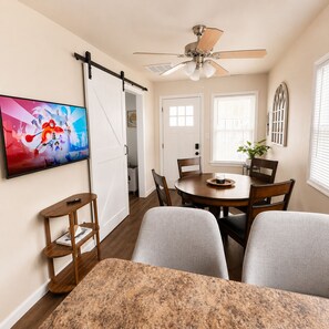 A dining area with a round table, chairs, a ceiling fan, and a TV mounted on the wall. - Spacious 3 Unit 7-bedroom house in Wildwood with Central AC (Wildwood)