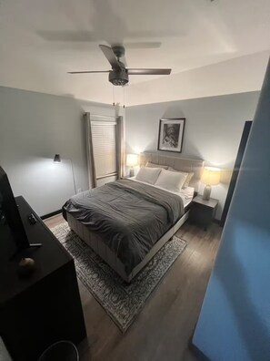 A bedroom with a bed, a ceiling fan, bedside lamps, a framed picture, and a desk with a lamp. - Entire home in Houston central, Texas (Houston)