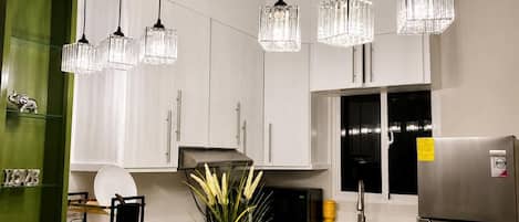 Une cuisine moderne avec des meubles de couleur verte, un réfrigérateur en acier inoxydable, un four à micro-ondes et une cuisinière à gaz.