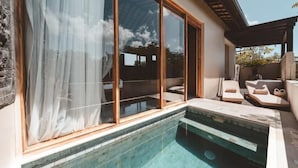 A poolside area with a clear view of the sky, a stone wall, and a wooden pergola. - Salty Lotus Hotel (Pecatu)