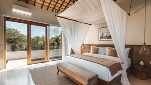 A bedroom with a canopy bed, a bench, a large window, and a framed picture on the wall. - Salty Lotus Hotel (Pecatu)