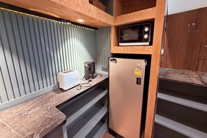 A compact kitchenette with a microwave, a refrigerator, a toaster, and a coffee maker. - M&M Rooftop Pattaya (Pattaya)