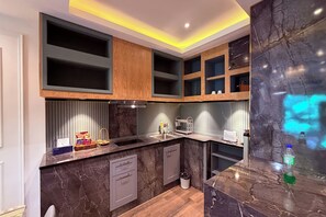 A modern kitchen with dark marble countertops, wooden cabinets, and built-in shelves. - M&M Rooftop Pattaya (Pattaya)