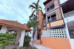 A multi-story residential building with a tiled roof, a gated entrance, and a staircase leading to the entrance. - M&M Rooftop Pattaya (Pattaya)
