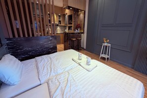A hotel room with a bed, a small bar area, and a seating space. - M&M Rooftop Pattaya (Pattaya)