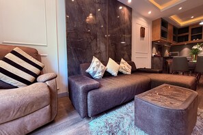 A modern living room with a sectional sofa, a striped armchair, and a coffee table. - M&M Rooftop Pattaya (Pattaya)